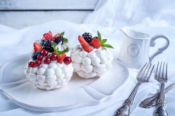 Delicate white meringues with fresh berries on the plate. Dessert Pavlova. Wedding cake.