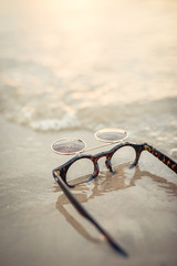 Fototapeta na wymiar Funny retro sunglasses laying in the water at the beach