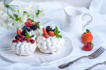 Delicate white meringues with fresh berries on the plate. Dessert Pavlova. A festive wedding cake.