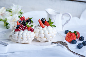 Delicate white meringues with fresh berries on the plate. Dessert Pavlova. Festive wedding cake.