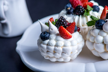 Delicate white meringues with fresh berries on the plate. Dessert Pavlova close-up. Wedding cake.