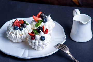 Delicate white meringues with fresh berries on the plate. Dessert Pavlova close-up. Wedding cake.