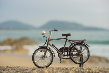 Fototapeta premium bicycle transport toy on sand sea beach in the evening sunset sky