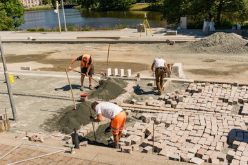Bauarbeiter verlegen ein Kopfsteinpflaster