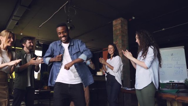 Slow Motion Of Happy Business Owner African American Young Man Dancing At Corporate Party With Employees Who Are Standing Around And Clapping Hands.