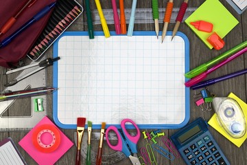 Back to school concept: school and office items with a white board on a wooden background.
