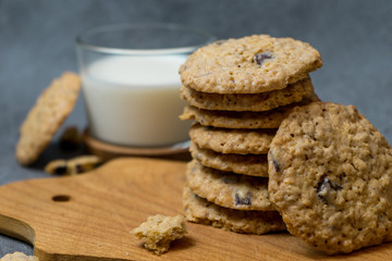 Oatmeal cookies and milk on a wooden board and gray background