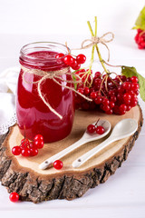 Glass jar of homemade viburnum jam with fresh berries  on white table.