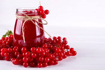 Glass jar of homemade viburnum jam with fresh berries  on white table.