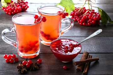 Hot spicy beverage with viburnum in glass cups  with fresh viburnum berries and cinnamon sticks, anise stars on a dark kitchen table.