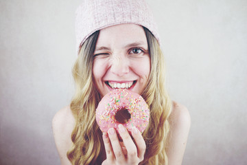Retrato divertido de una mujer joven y rubia con un donut rosa 