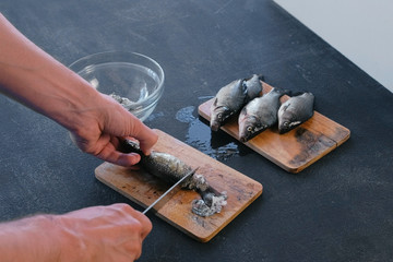 Man cleans carp from the scales. Close-up hands. Cooking a fish.