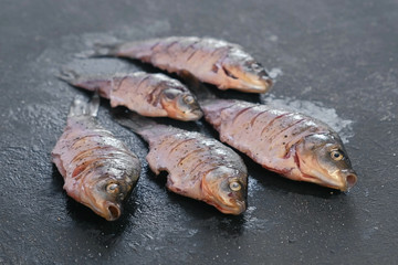 Carp in spices on a black table close-up. Top view.