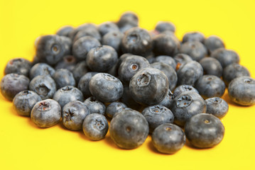 Heap of blueberries isolated on yellow colorful background. Summer vibe fruit berry with copy space. Ingredient for breakfast.