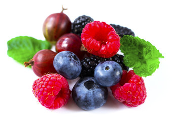 Close-up arrangement mixed, assorted berries including blackberries, strawberry, blueberry, raspberries and fresh leaf on white