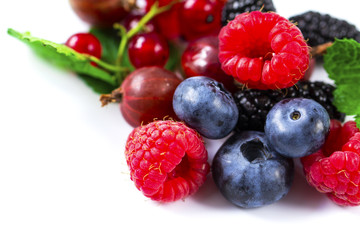 Close-up arrangement mixed, assorted berries including blackberries, strawberry, blueberry, raspberries and fresh leaf on white