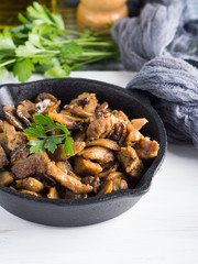 Turkey meat stew with champignon mushrooms and spices served in cast iron skillet on white wooden board
