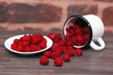 raspberries scattered from an enamel cup