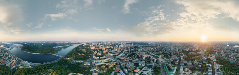 Naklejka na ściany i meble A big 360 degrees panorama of the city of Kiev at sunset. A modern metropolis in the center of Europe against the backdrop of sunset sky from a bird's eye view. Aerial view. Panorama of the Tourist