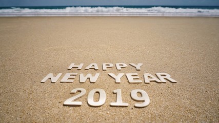 New Year Concept - ‘Happy New Year 2019’ made of arranged wooden letters on beach sand. With background of a beach.