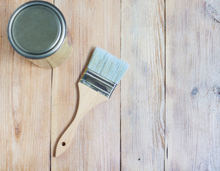 Painting brush near a metal jar with  paint on a wooden table