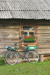 Bicycle parked against the wooden wall with window and flower box