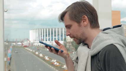 Handsome stylish man student freelancer leaving message using voice recognition, speaking at smartphone on street. Helper find stadium background - Powered by Adobe