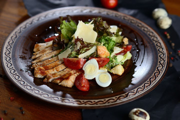 Caesar salad with chicken, parmesan and cherry on a wooden table