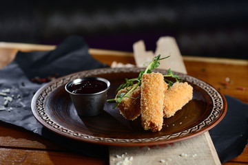 cheese sticks in batter with berry sauce on a wooden table