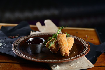 cheese sticks in batter with berry sauce on a wooden table