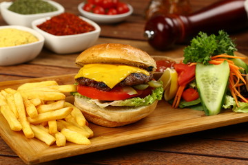 Tasty Cheeseburger and french fries on wood plate