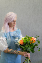 A young girl-florist comes up and makes a bouquet. Beautiful girl with a bouquet of flowers in the nature