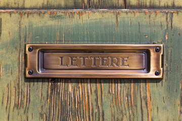 close-up brushed copper letter box on old painted wood