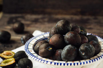 Fresh and ripe plums on a plate on a wooden background, macro, selective focus