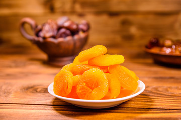 Dried apricots and date fruits on wooden table