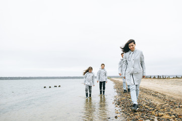 Beautiful family portrait dressed in raincoatnear the sea