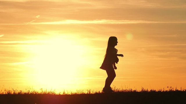 Little girl with teddy bear at sunset. Silhouette girl holding a bear doll bear watching the sunset. Concept big dream.