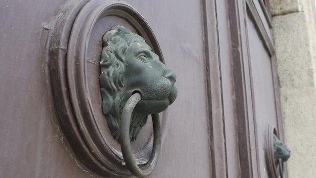 Woman knows on an old vintage door with a lion shaped knocker.