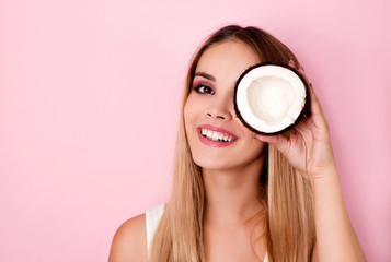 Happy young woman holding coconut piece in front of eye - Powered by Adobe