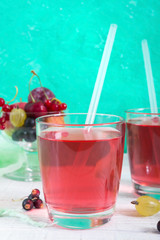 Berry compote. Fruit vitamin drink in glass and ripe fresh berries on a bright background. Vertical view