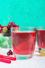 Berry compote. Fruit vitamin drink in glass and ripe fresh berries on a bright background. Vertical view