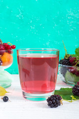 Berry compote. Fruit vitamin drink in glass and ripe fresh berries on a bright background. Vertical view