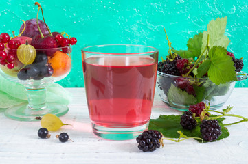Berry compote. Fruit vitamin drink in glass and ripe fresh berries on a bright background.