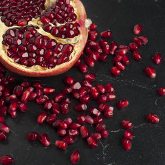 Juicy pieces of pomegranate on a black marble board