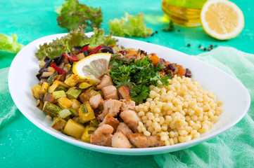 Delicious oriental salad tabbouleh. Couscous with fried vegetables and chicken on a white plate. Traditional Lebanese appetizer.