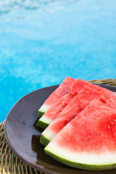 Ripe Juicy Seedless Watermelon Cut in Slices Wedges on Plate on Rattan Table by Swimming Pool. Sunlight. Seaside Vacation Relaxation Wanderlust Summer Vibes. Authentic Atmosphere. Lifestyle. Poster