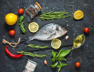 Raw fresh dorado with lemon on dark stone background.