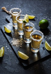 Mexican gold tequila with lime and salt on black stone background. © voloshin311