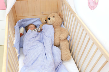 Ein zweijähriger Junge in seinem Kinderbett