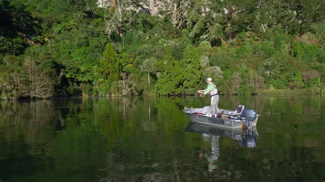 Fisherman fly fishing for trout from a boat on Lake Whakamaru in New Zealand